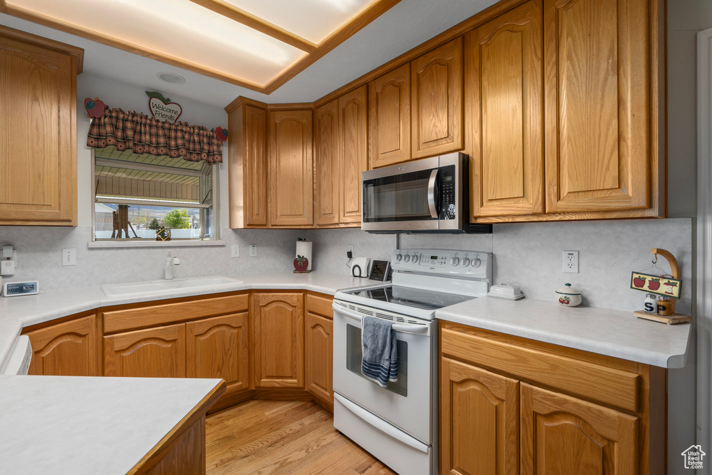 Kitchen with tasteful backsplash, light hardwood / wood-style flooring, sink, and white electric range