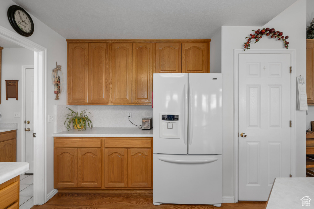 Kitchen with hardwood / wood-style floors and white refrigerator with ice dispenser