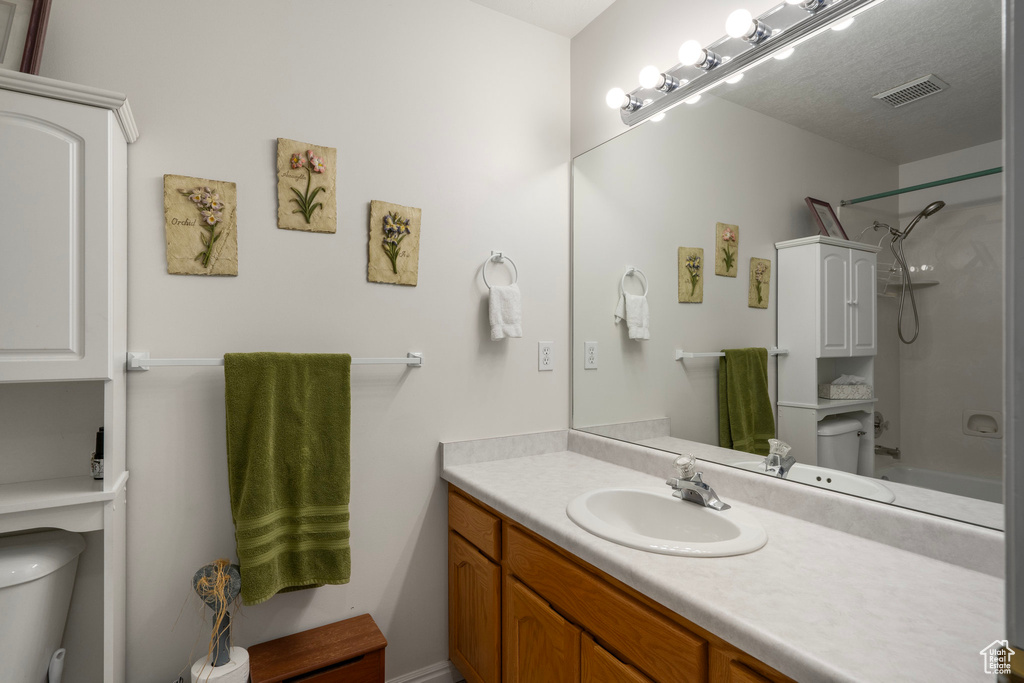 Full bathroom featuring a textured ceiling, vanity, bathing tub / shower combination, and toilet