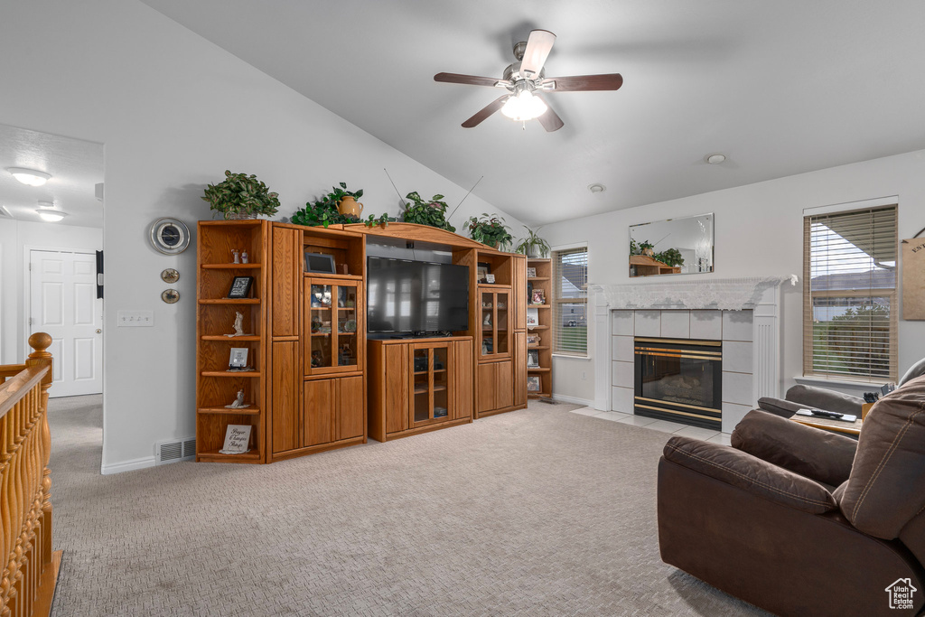 Carpeted living room with ceiling fan, a fireplace, and lofted ceiling