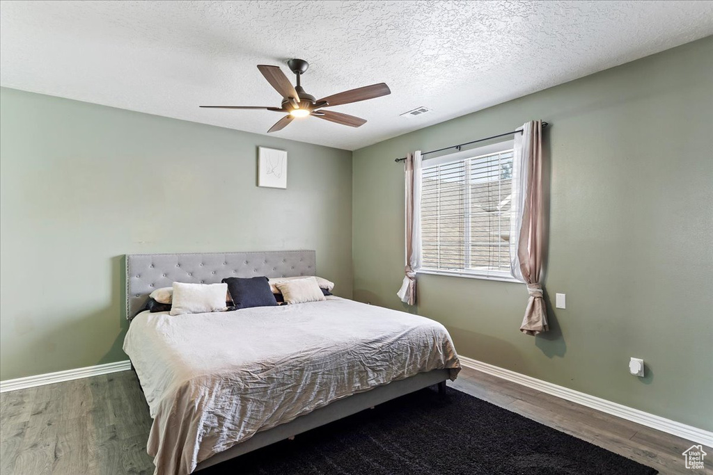 Bedroom featuring ceiling fan, dark wood-type flooring, and a textured ceiling