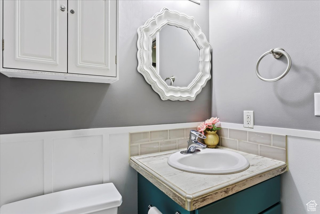 Bathroom featuring backsplash, large vanity, and toilet