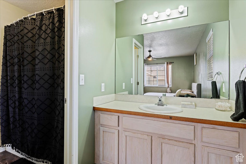Bathroom featuring wood-type flooring, a textured ceiling, oversized vanity, and ceiling fan