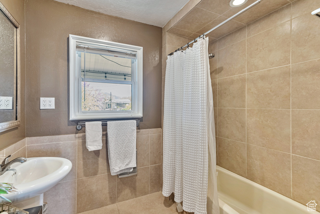 Bathroom with tile flooring, sink, tile walls, and shower / tub combo with curtain