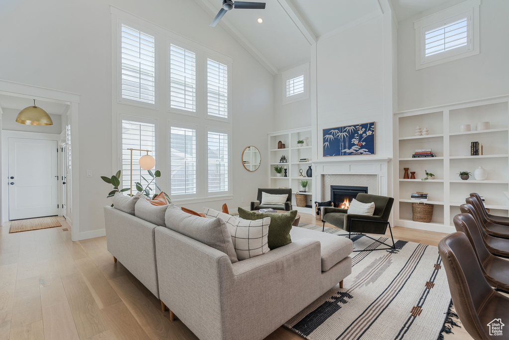 Living room featuring ceiling fan, high vaulted ceiling, and light wood-type flooring