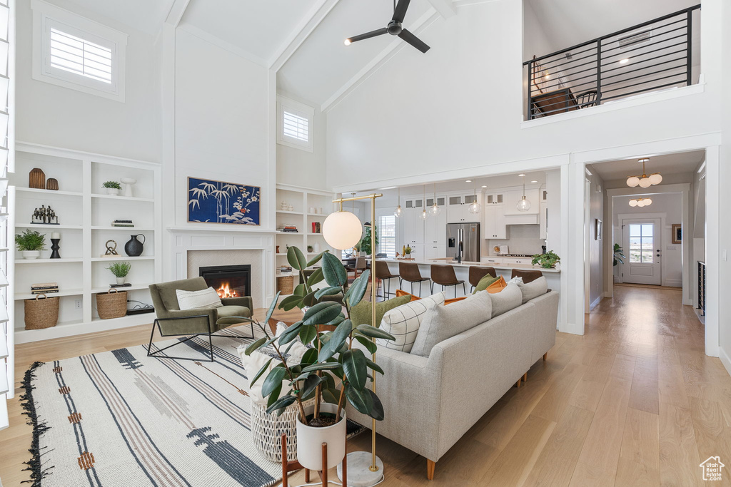 Living room featuring a healthy amount of sunlight, light hardwood / wood-style flooring, ceiling fan, and high vaulted ceiling