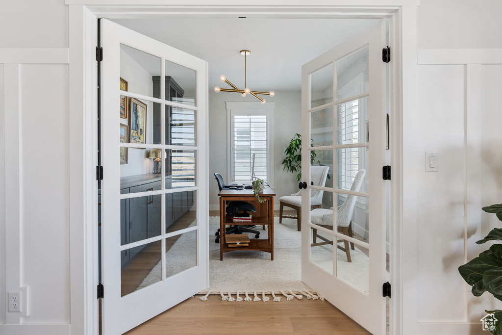 Entryway with french doors, a notable chandelier, and light wood-type flooring