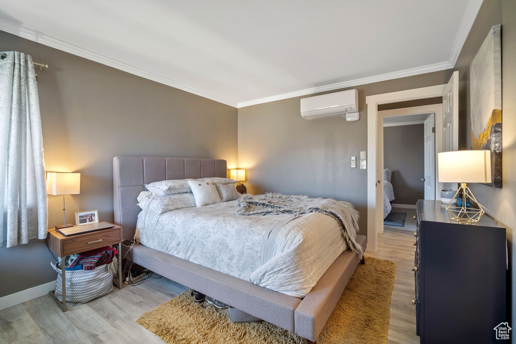 Bedroom featuring crown molding, light hardwood / wood-style floors, and a wall mounted air conditioner