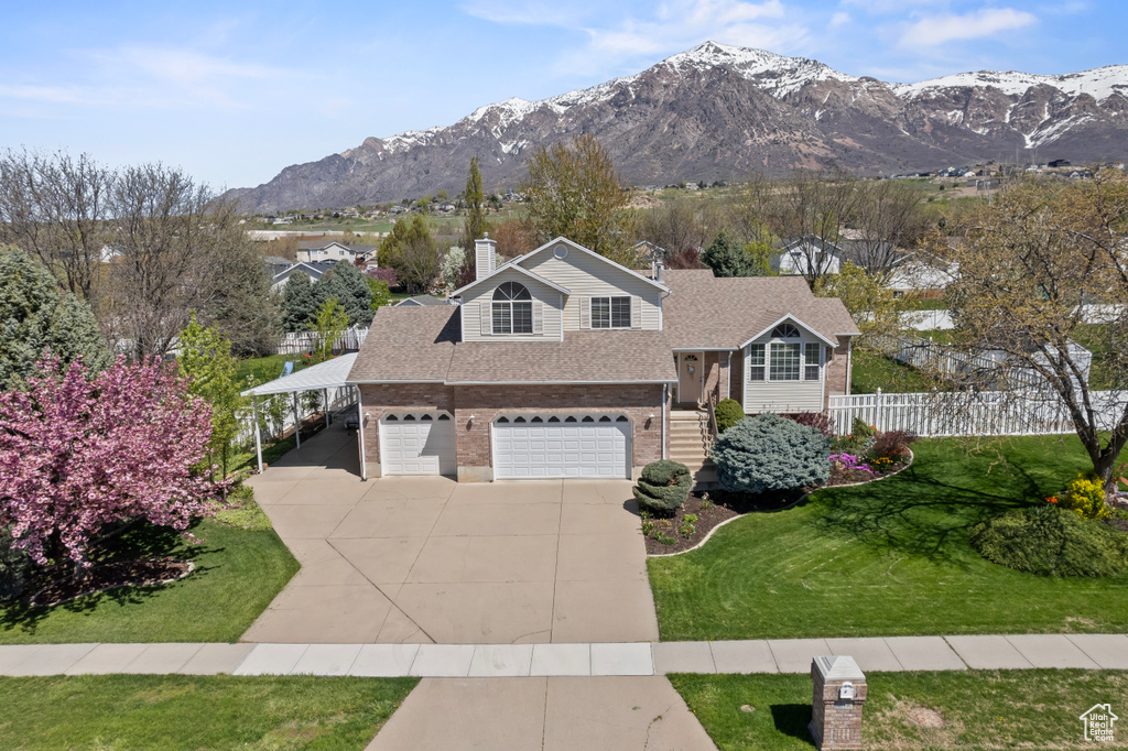View of front of home featuring a garage, a mountain view, and a front lawn