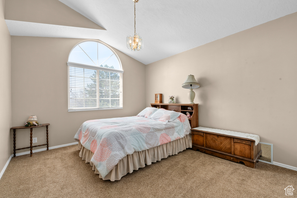 Carpeted bedroom featuring vaulted ceiling and an inviting chandelier