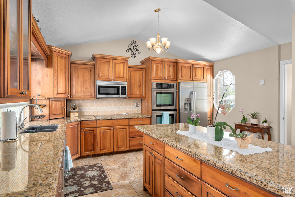 Kitchen with backsplash, vaulted ceiling, stainless steel appliances, light tile flooring, and sink