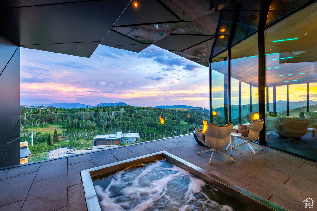 Patio terrace at dusk featuring an outdoor hot tub and a mountain view