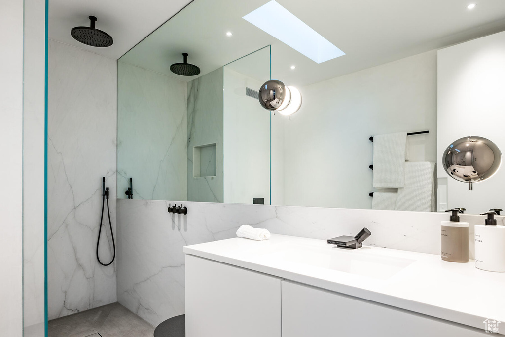 Bathroom featuring a skylight, a tile shower, and large vanity