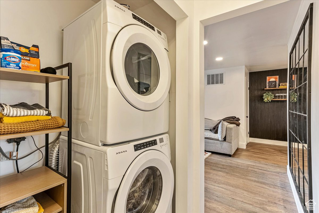 Clothes washing area featuring wood-type flooring and stacked washer / dryer