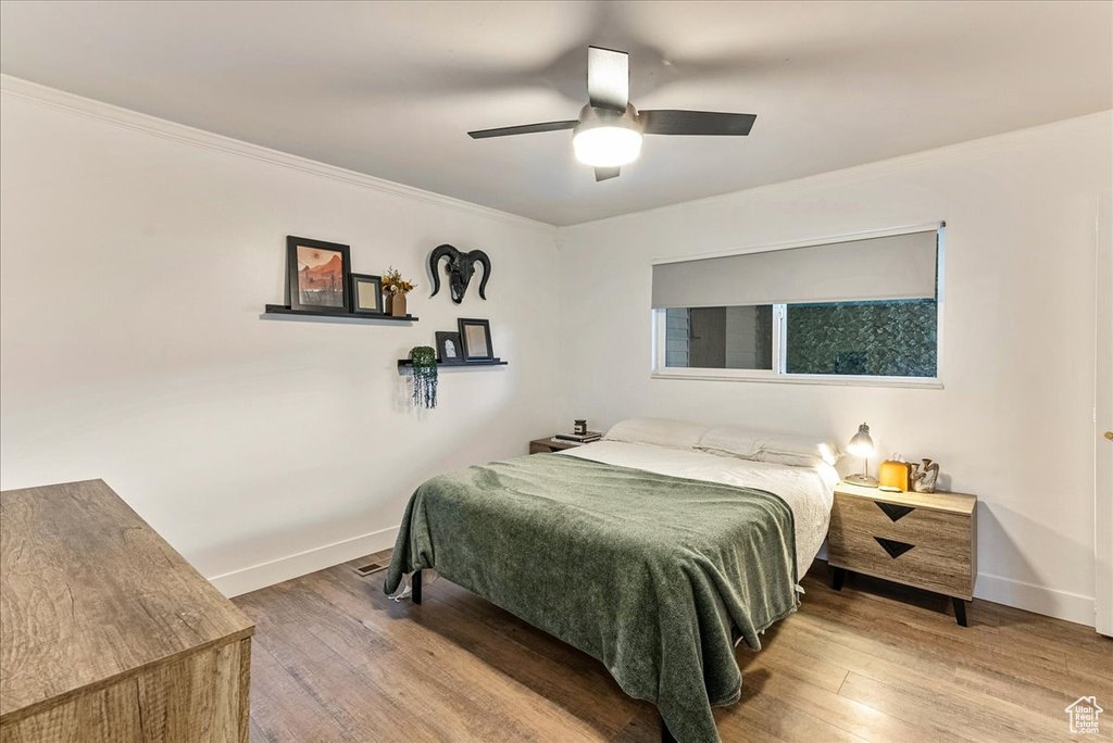 Bedroom featuring wood-type flooring, ceiling fan, and ornamental molding