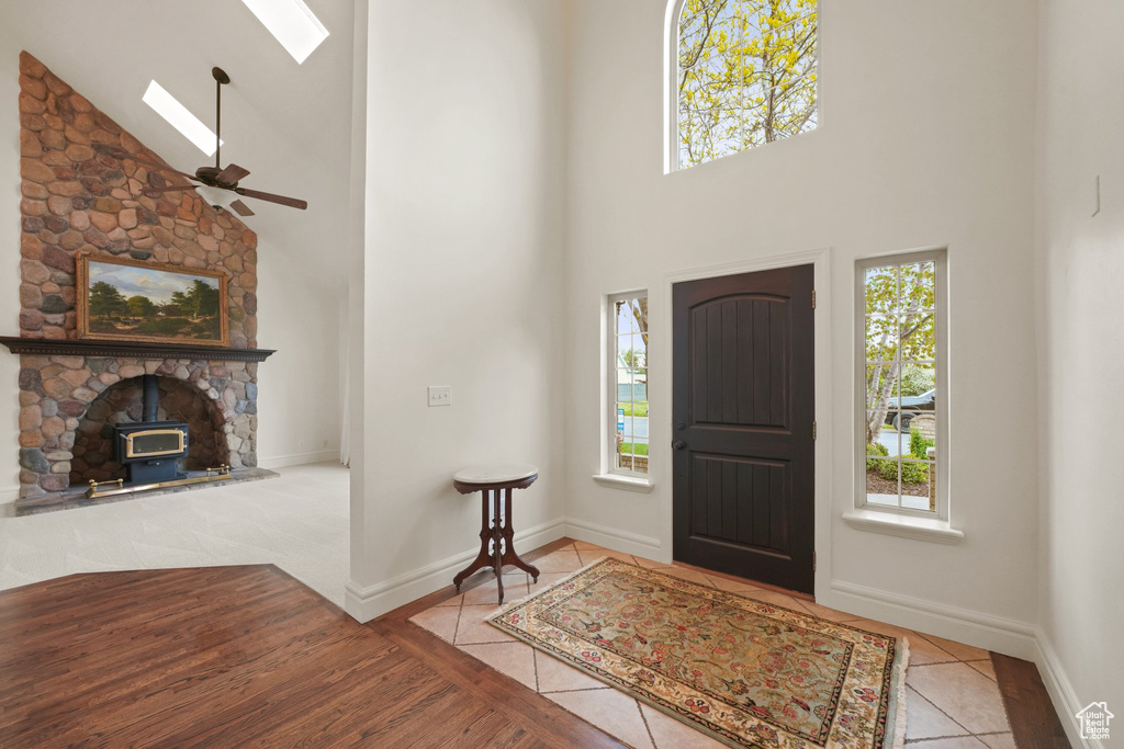 Entrance foyer with high vaulted ceiling, ceiling fan, a skylight, a wood stove, and tile floors
