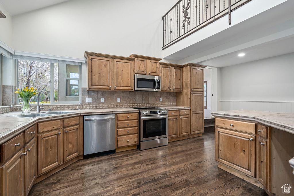 Kitchen featuring sink, tile counters, stainless steel appliances, and dark hardwood / wood-style floors