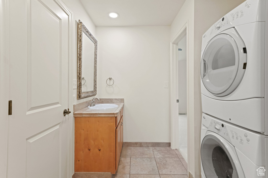 Laundry room with sink, stacked washer / dryer, and light tile floors
