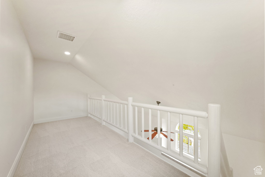 Additional living space featuring light carpet and vaulted ceiling