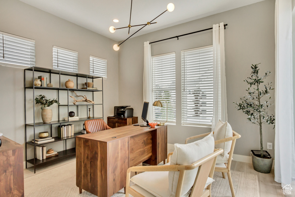 Office space featuring a wealth of natural light, light hardwood / wood-style flooring, and a chandelier