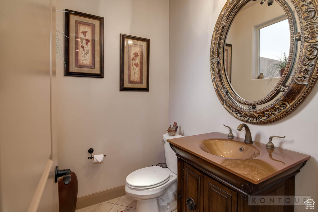 Bathroom featuring vanity with extensive cabinet space, toilet, and tile flooring