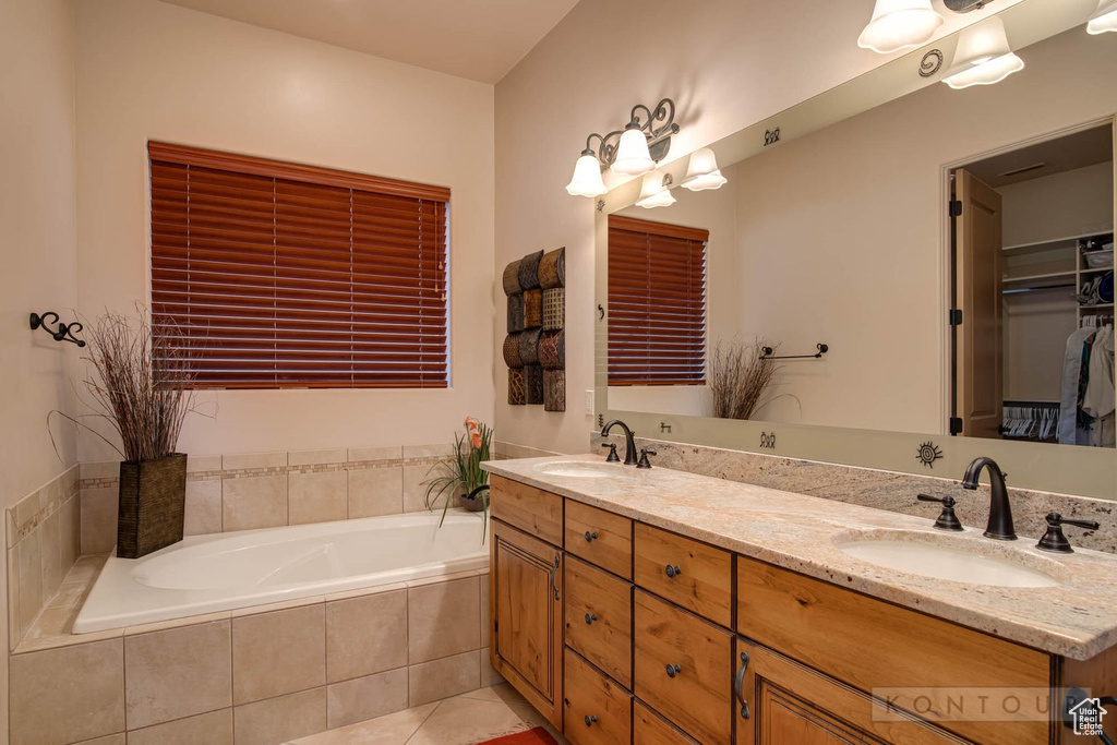Bathroom featuring tile floors, dual vanity, and tiled bath