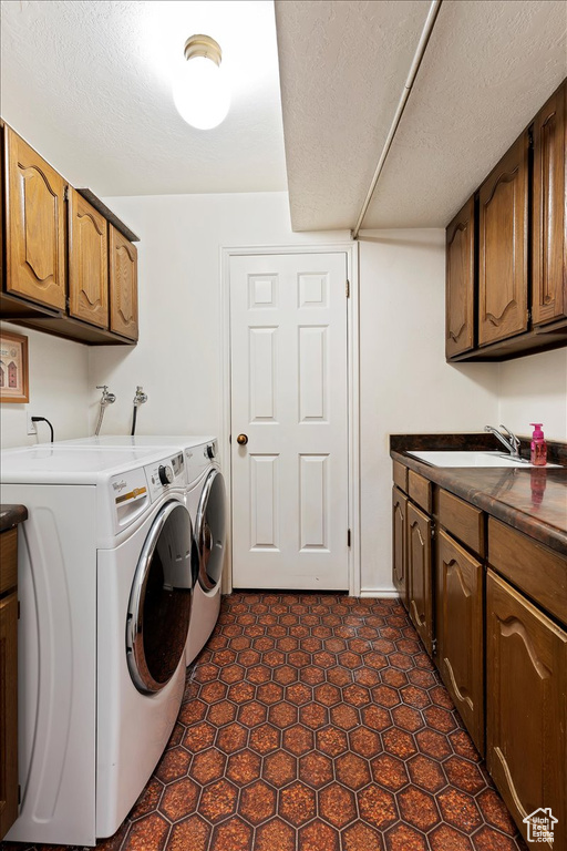 Laundry area featuring cabinets, dark tile flooring, a textured ceiling, and washer and clothes dryer