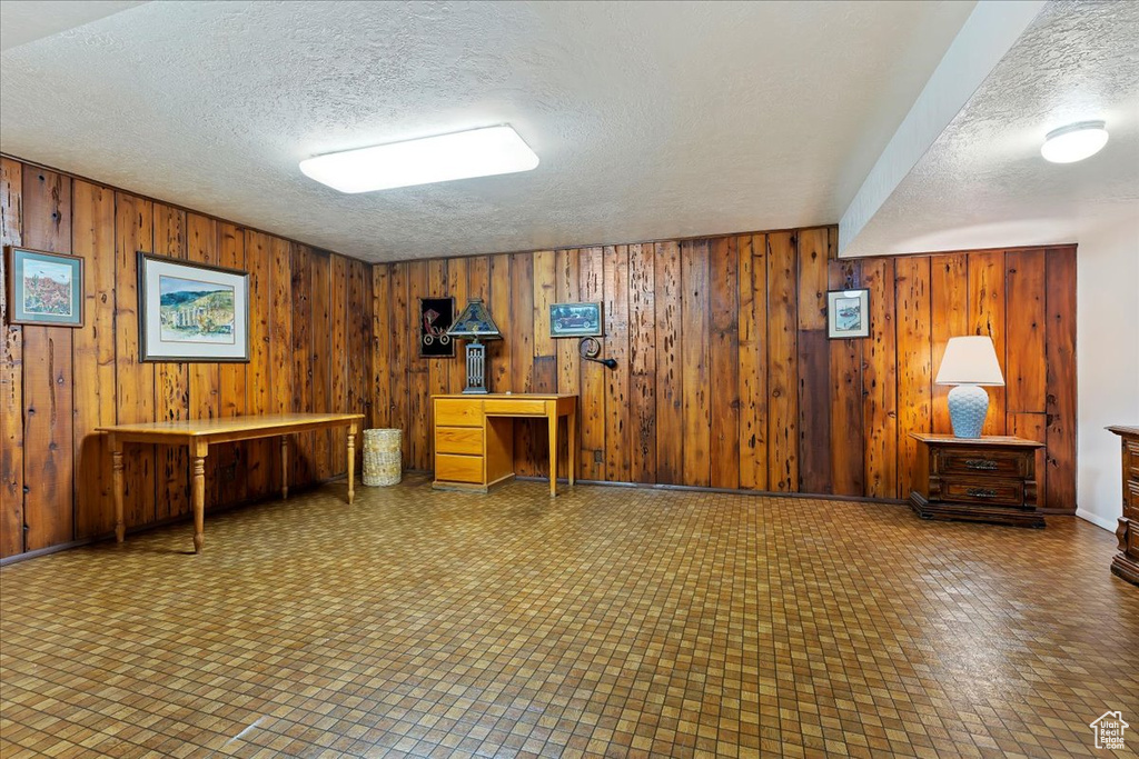 Miscellaneous room featuring a textured ceiling, tile floors, and wooden walls