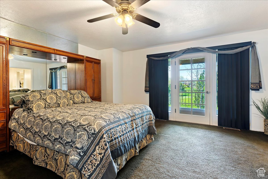 Bedroom with ceiling fan, carpet, access to exterior, and a textured ceiling