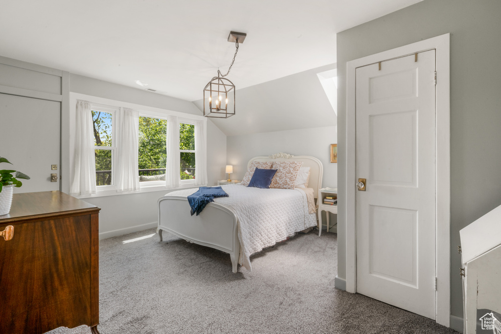 Bedroom with vaulted ceiling, carpet floors, and a notable chandelier