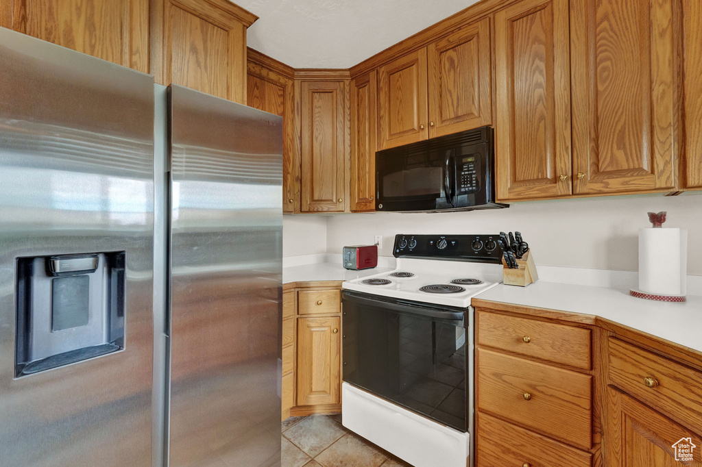 Kitchen with high quality fridge, light tile floors, and white electric range