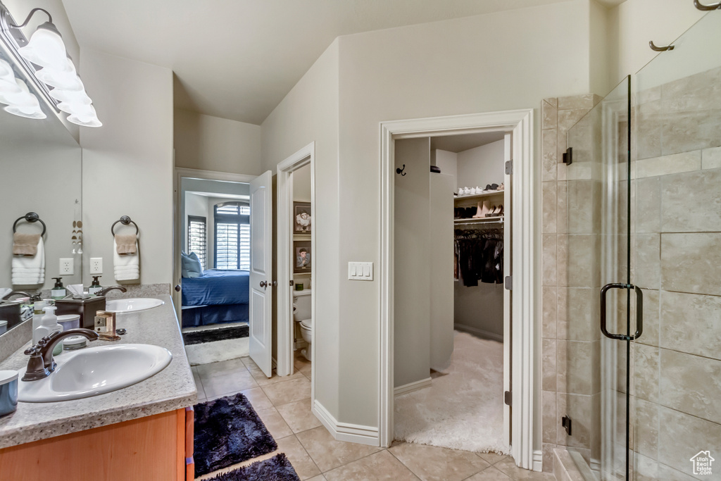 Bathroom featuring an enclosed shower, double large sink vanity, mirror, and light tile floors