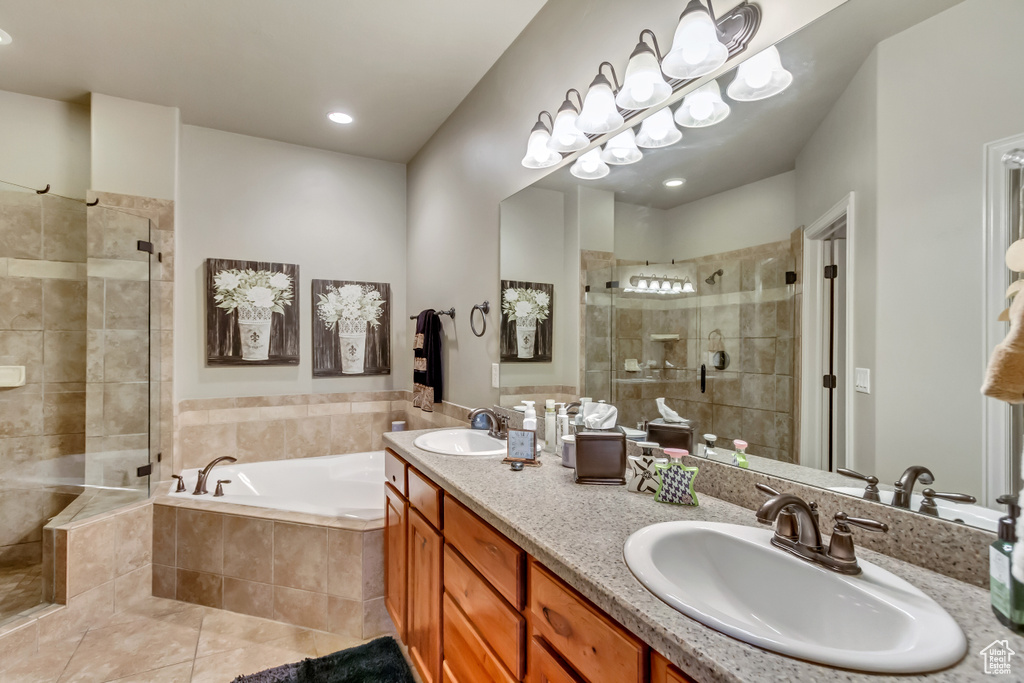 Bathroom with mirror, double sink vanity, shower with separate bathtub, and light tile floors