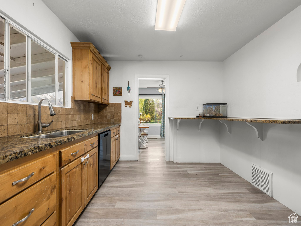 Kitchen with a kitchen breakfast bar, light hardwood / wood-style flooring, backsplash, sink, and dishwasher