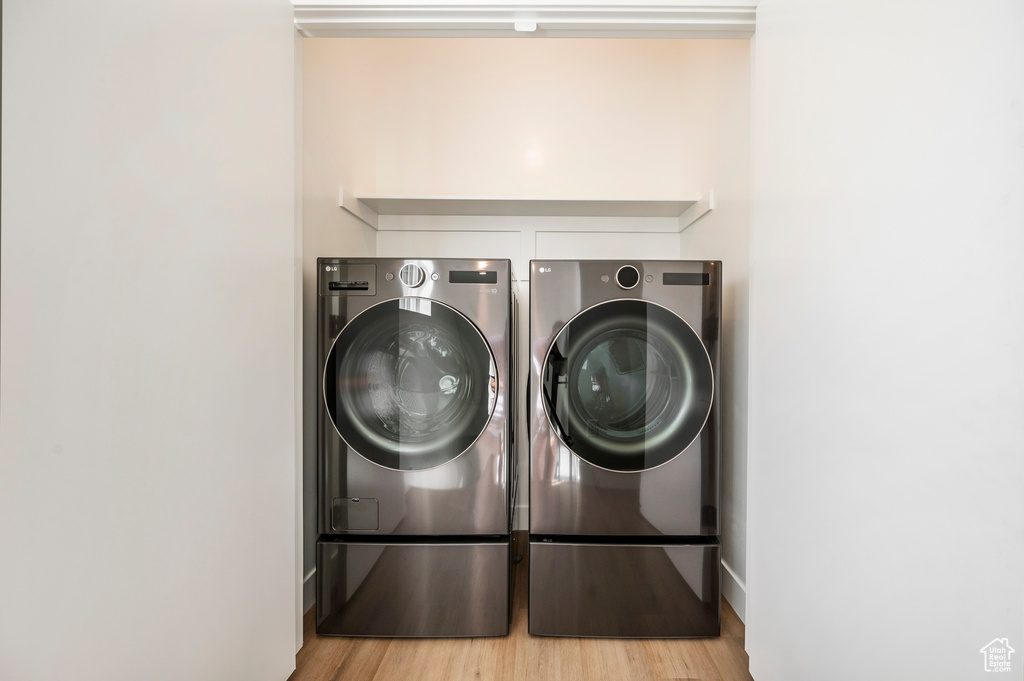 Laundry area with light wood-type flooring and washing machine and clothes dryer