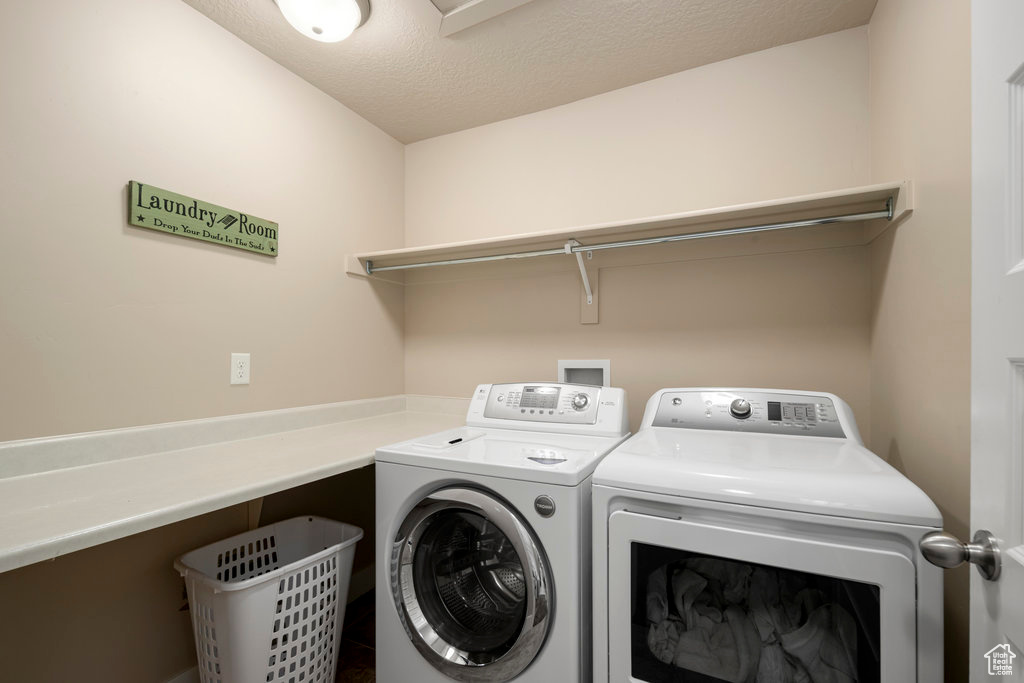 Laundry area featuring washer and clothes dryer, washer hookup, and a textured ceiling