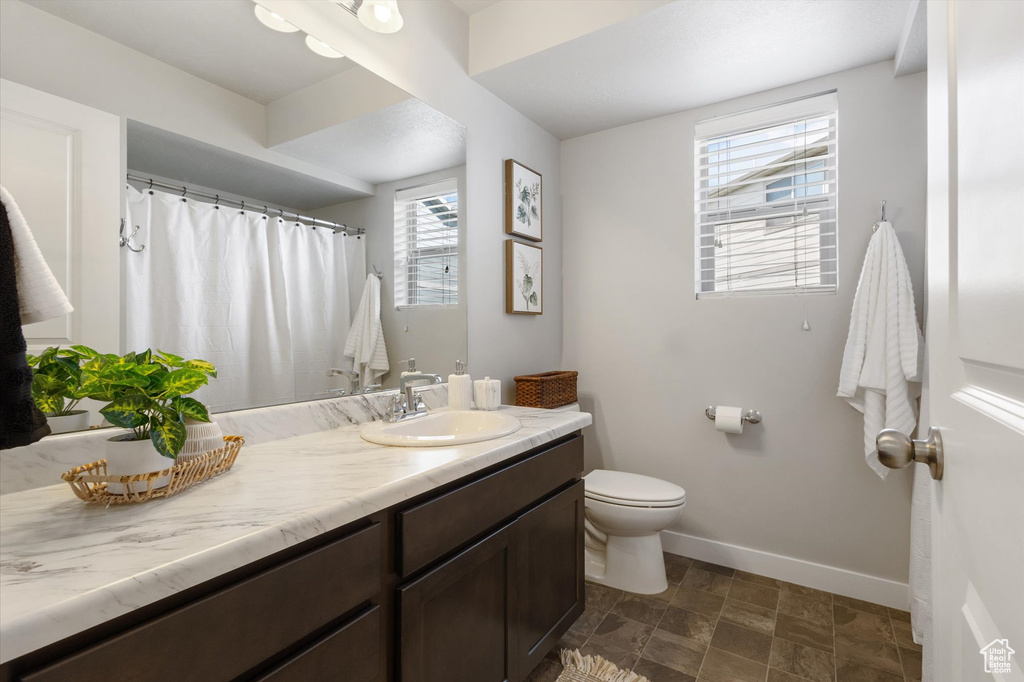 Bathroom with a wealth of natural light, large vanity, toilet, and tile flooring
