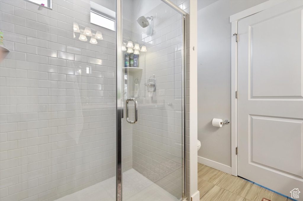 Bathroom with an enclosed shower, tile floors, and toilet