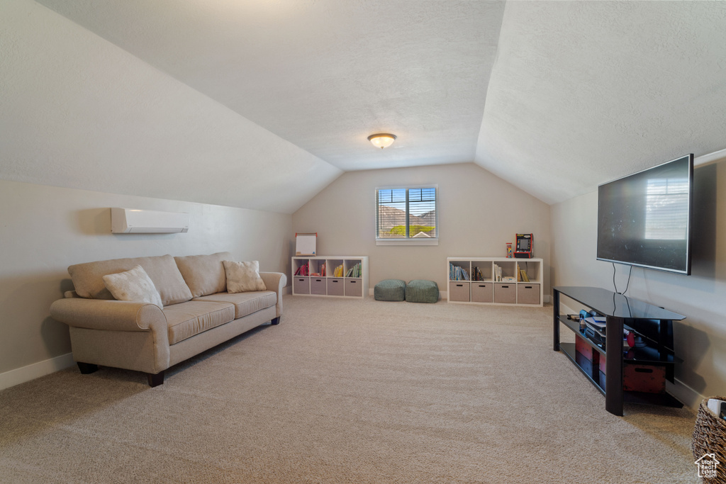 Carpeted living room featuring lofted ceiling and a wall mounted air conditioner