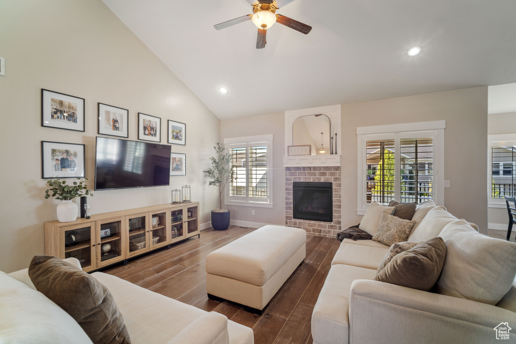 Living room with dark hardwood / wood-style flooring, plenty of natural light, a brick fireplace, and ceiling fan
