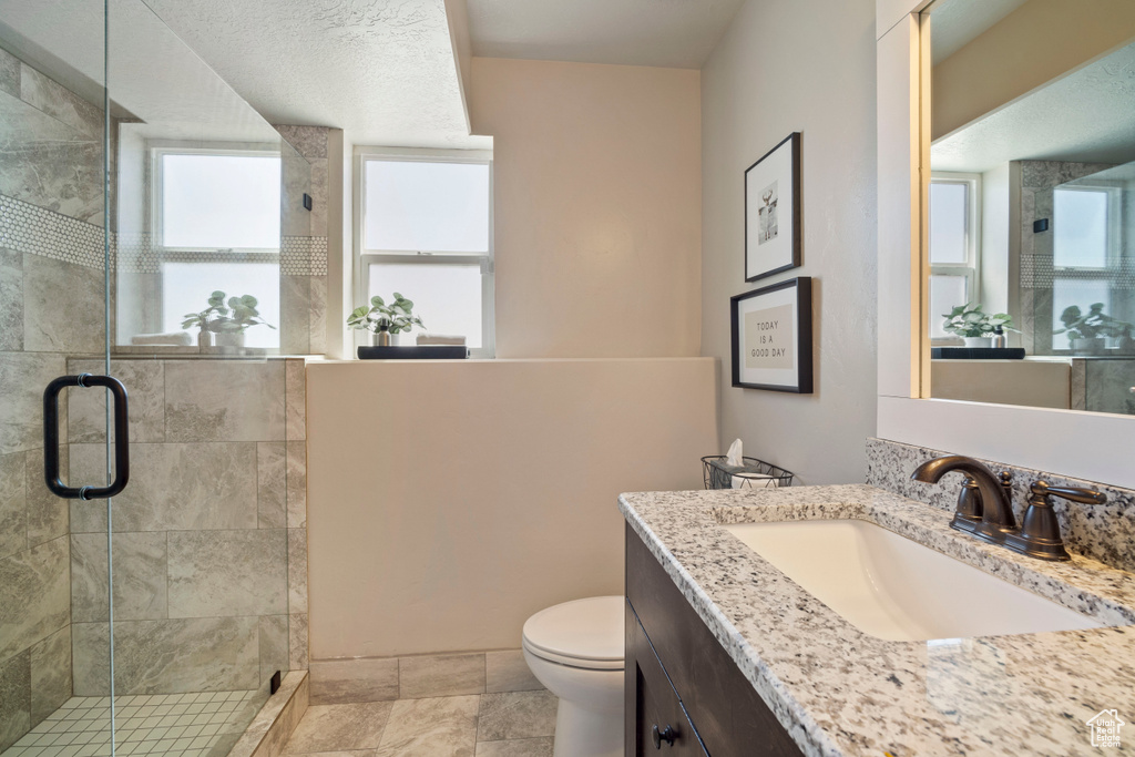 Bathroom featuring walk in shower, oversized vanity, toilet, and tile flooring