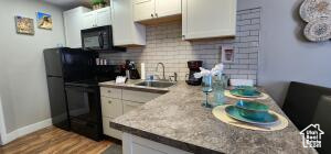 Kitchen featuring backsplash, sink, white cabinetry, and hardwood / wood-style floors