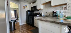 Kitchen featuring backsplash, white cabinetry, and dark wood-type flooring