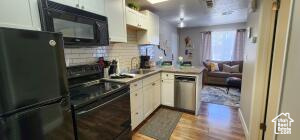 Kitchen featuring white cabinets, light hardwood / wood-style floors, kitchen peninsula, and black appliances