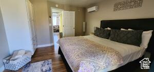 Bedroom with a wall mounted air conditioner and dark hardwood / wood-style floors