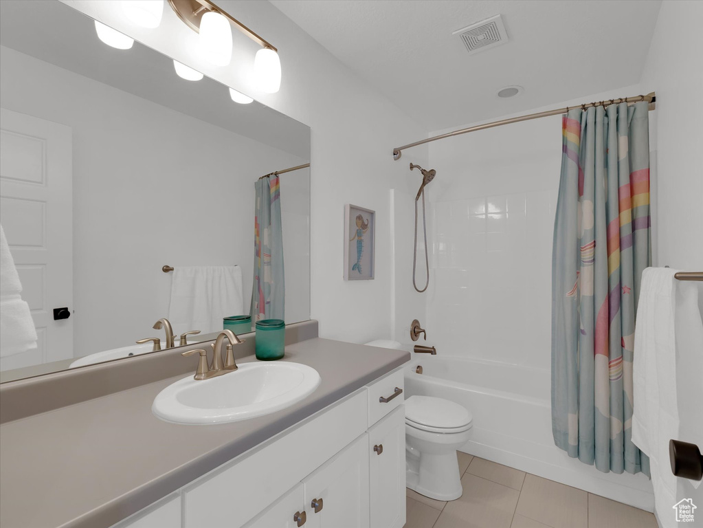 Full bathroom with tile flooring, oversized vanity, toilet, and shower / bathtub combination with curtain