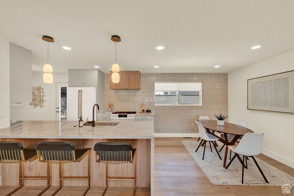 Kitchen featuring hanging light fixtures, sink, light wood-type flooring, and white appliances