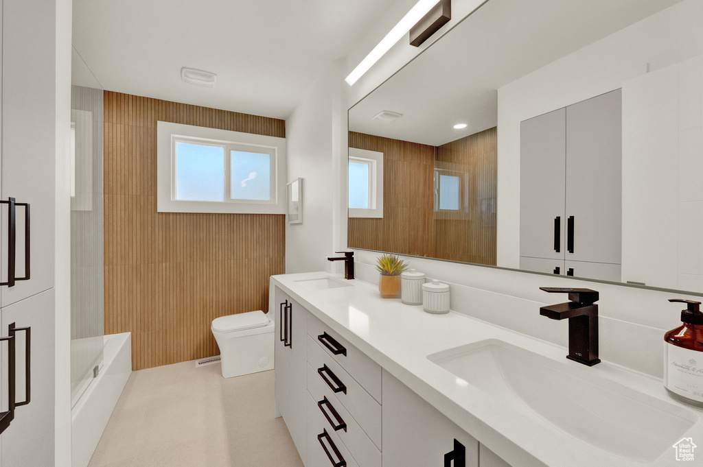 Bathroom with double vanity, wooden walls, and toilet