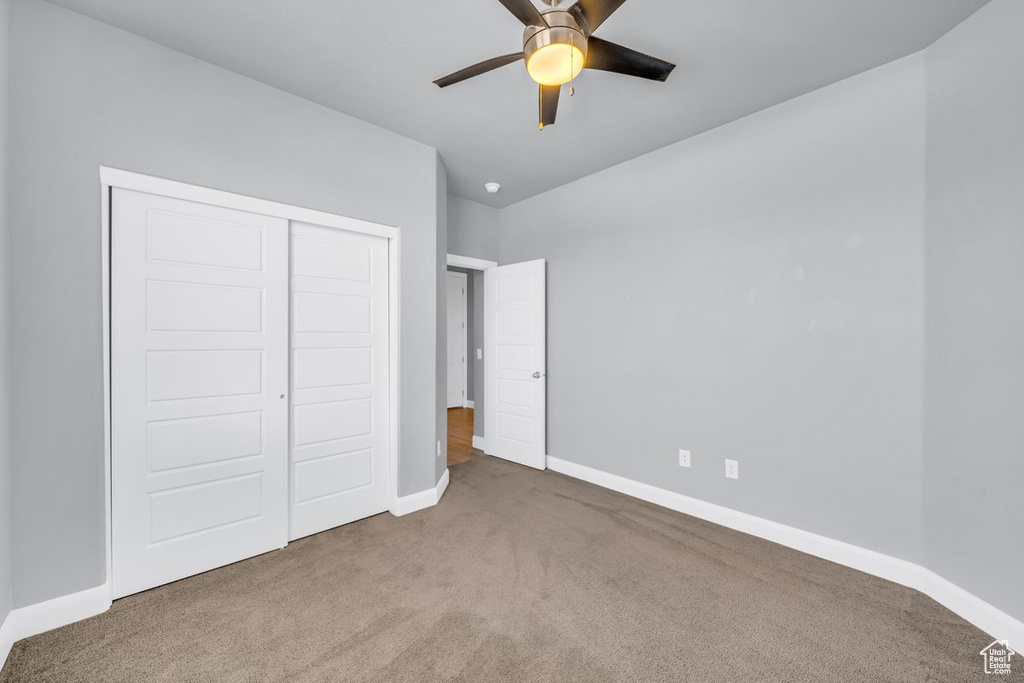 Unfurnished bedroom featuring a closet, ceiling fan, carpet floors, and lofted ceiling