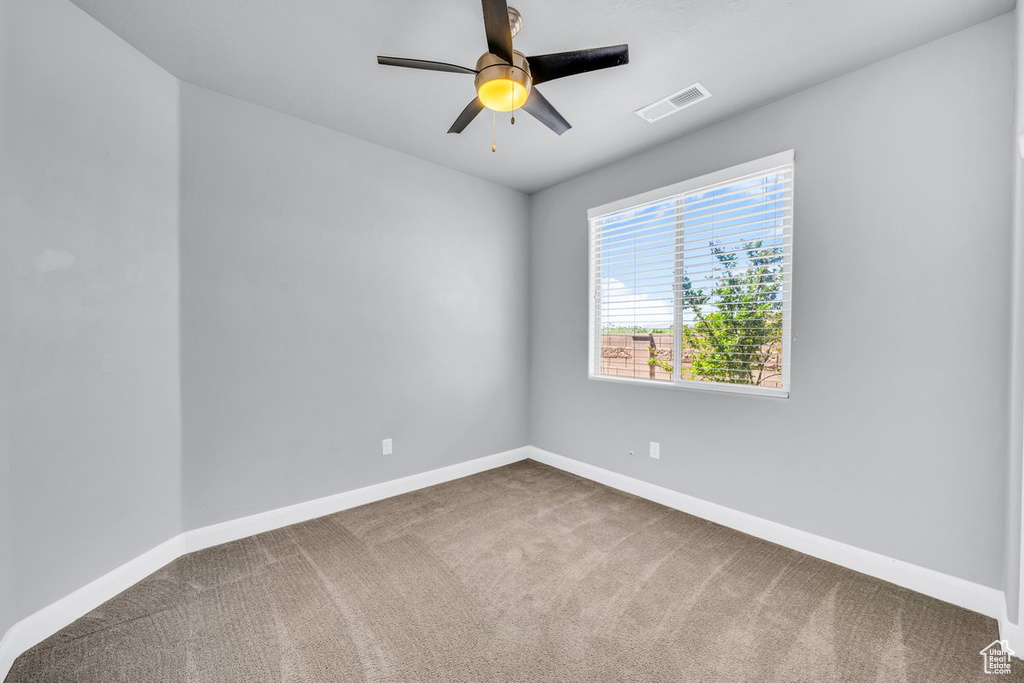 Unfurnished room featuring ceiling fan and dark carpet